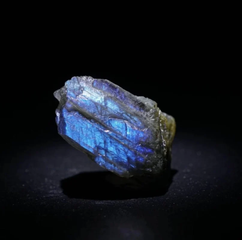 Polished moonstone cabochon showing blue adularescence, soft natural lighting, dark background