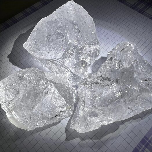 A clear milky white quartz crystal displaying vivid rainbow spectral flashes across its fractured internal structure under direct light