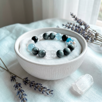Detail of the sugar-cube clear quartz carved barrel bead with traditional Chinese auspicious motifs on the Morning Mist bracelet.
