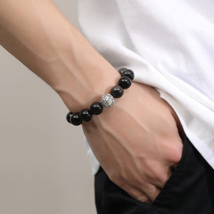 Close-up detail of S925 silver Fu character bead on Black Obsidian bracelet, engraved fortune symbol silver bead detail