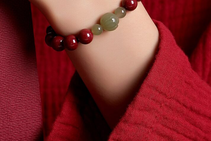 Close-up on the carved lotus jade bead showing the petal detail, the smooth jade surface, and the transition to the flanking cinnabar beads.