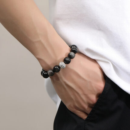 Close-up detail of S925 silver auspicious cloud bead on Black Obsidian bracelet, carved Xiangyun symbol, delicate silver cloud jewelry detail