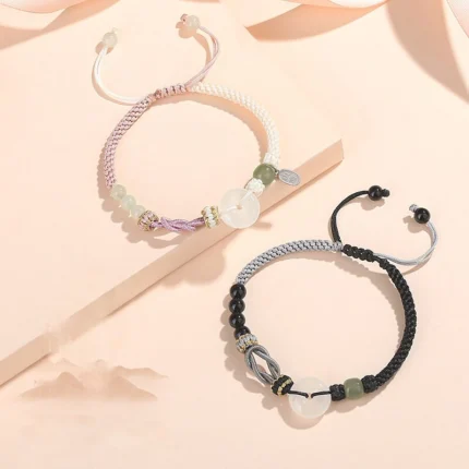 Both bracelets laid flat side by side on a neutral background — pink version on the left, black version on the right — showing the matching peace circles and Peru knot detail clearly.