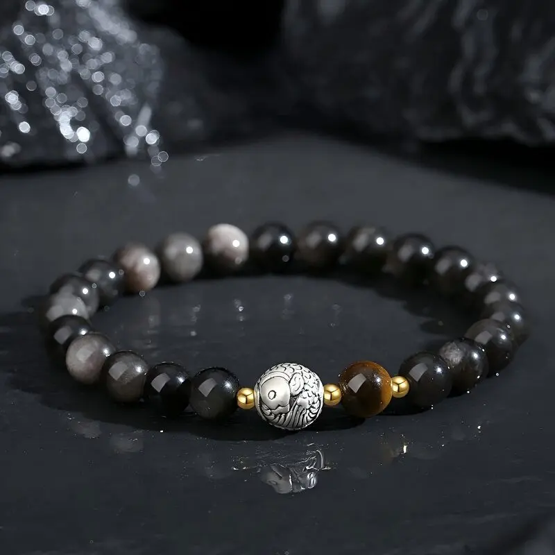 Polished black obsidian beaded bracelet with golden Tiger's Eye focal beads and sterling silver koi fish charm, dark background, natural lighting
