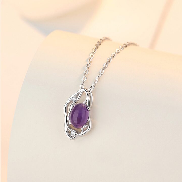 Close-up of natural amethyst cabochon showing violet purple color and natural internal zoning, in polished silver open-work setting