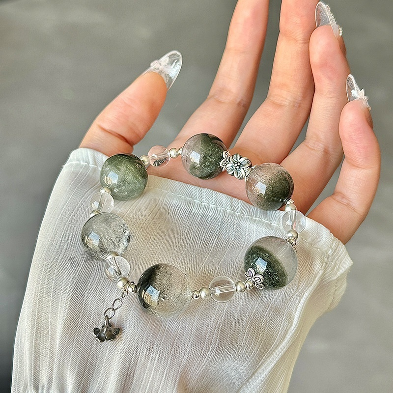 Close-up detail of Green Phantom Crystal beads showing green phantom inclusions inside clear quartz, antique silver floral bead accents