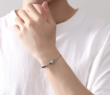 The contrasting braided black cord and fine silver cable chain on either side of the crane charm.