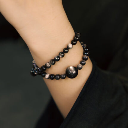 Golden obsidian double-wrap bracelet worn on wrist, everyday bold styling, dark studio or natural outdoor setting, gender neutral crystal jewelry, volcanic glass bracelet