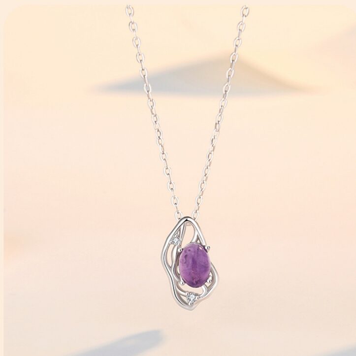 Natural amethyst oval cabochon pendant in water-ripple open-work silver setting, high-polish finish, on white linen, soft purple tones