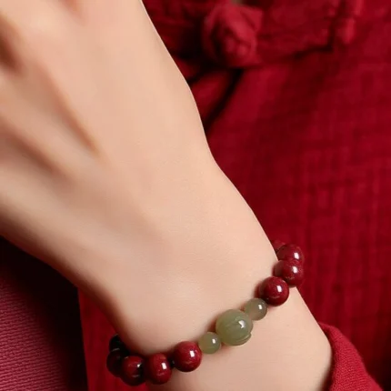Wrist-shot in natural light showing the weight and presence of the bracelet on the wrist. Evening or warm indoor lighting preferred to show the cinnabar depth.