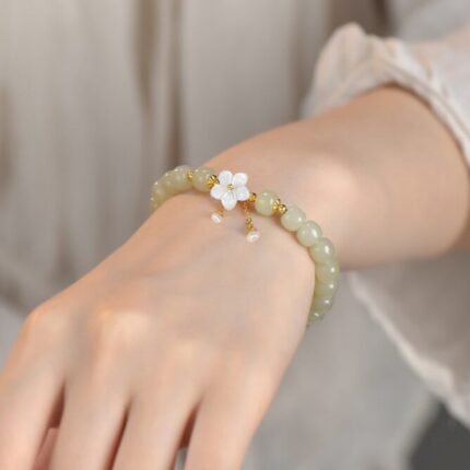 Wrist-shot in natural light — the bracelet worn at mid-height in a simple, neutral setting. Show the movement of the tassel.