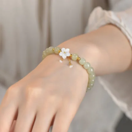 Wrist-shot in natural light — the bracelet worn at mid-height in a simple, neutral setting. Show the movement of the tassel.