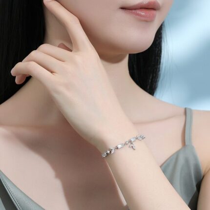 Wrist-shot in natural light — fine chain and frosted white agate beads visible on the wrist. Cool, neutral setting.