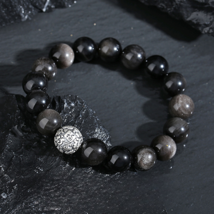 Black Obsidian Fu character bracelet styled on wrist, everyday protective wear, natural light photography, quiet dark jewelry aesthetic