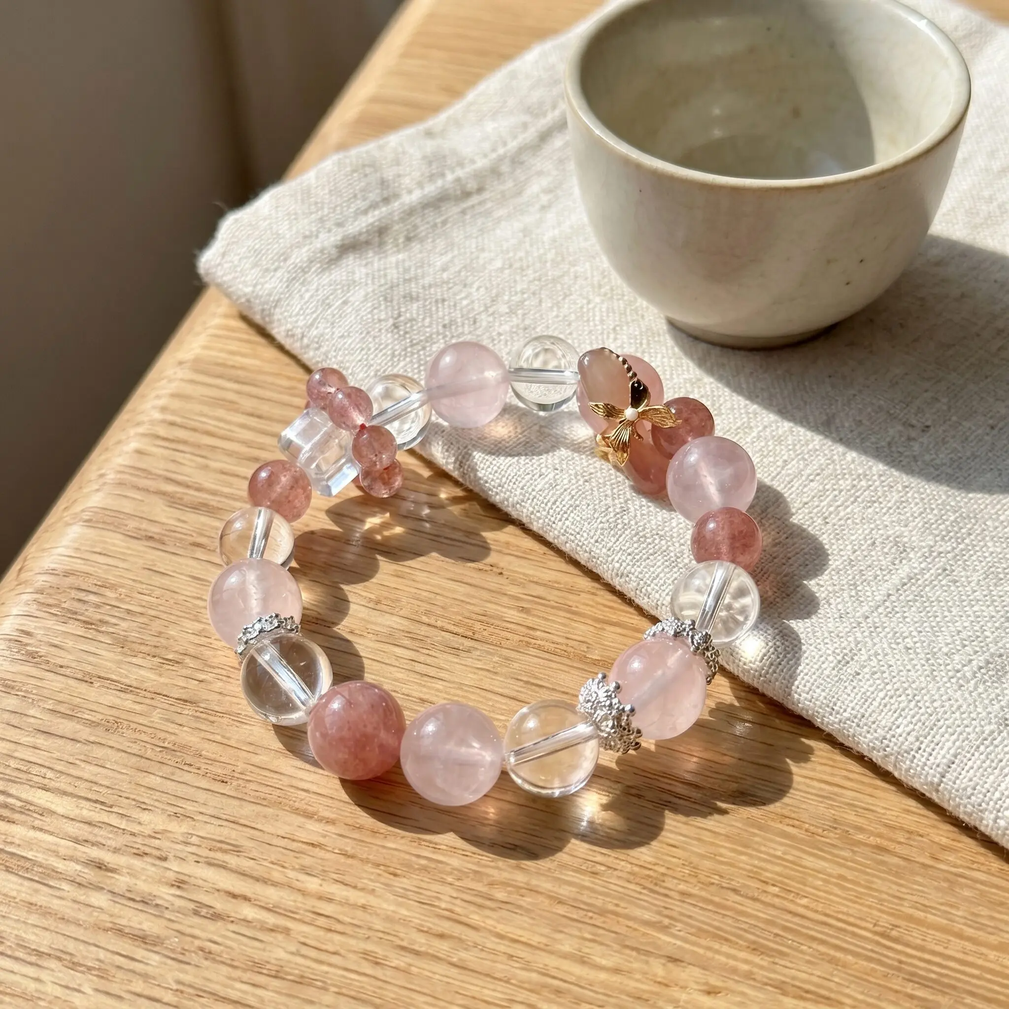 Square-cut faceted clear quartz bead with small strawberry quartz bead cluster beside, geometric multi-faceted crystal accent, strawberry quartz cluster detail, silver spacer beads