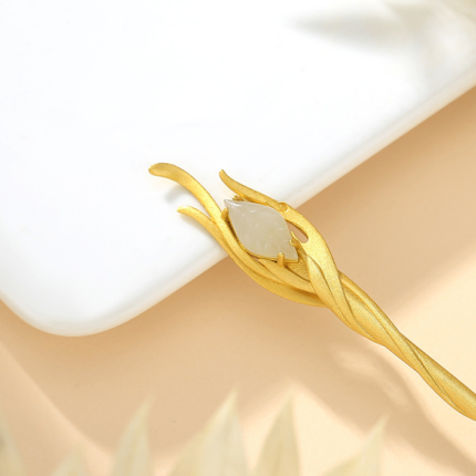 Close-up of phoenix feather hairpin head, gold-plated silver prongs holding white Hetian jade marquise stone, detail of traditional feather motif jewelry