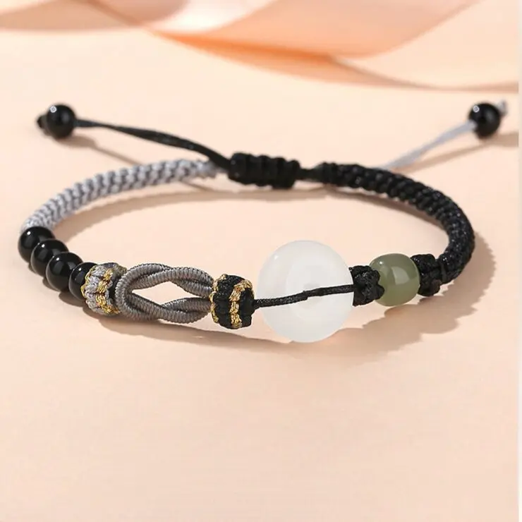 A matched pair of Peru-knotted braided cord bracelets — hers in soft pink with Hetian jade beads, his in deep black with black agate — both featuring a white agate peace circle, laid flat side by side on a white background.