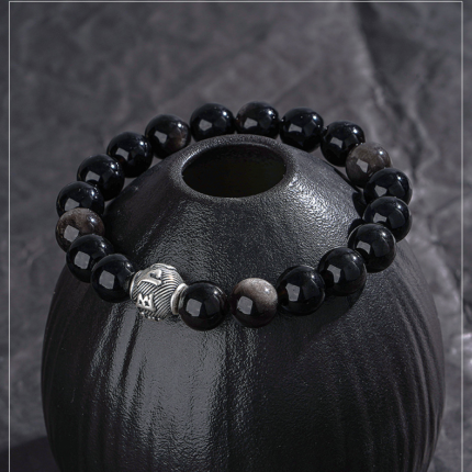 Black Obsidian volcanic glass bead detail, deep jet black polished surface, natural grey veining, glossy mineral specimen