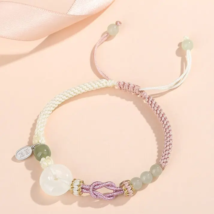 A matched pair of Peru-knotted braided cord bracelets — hers in soft pink with Hetian jade beads, his in deep black with black agate — both featuring a white agate peace circle, laid flat side by side on a white background.