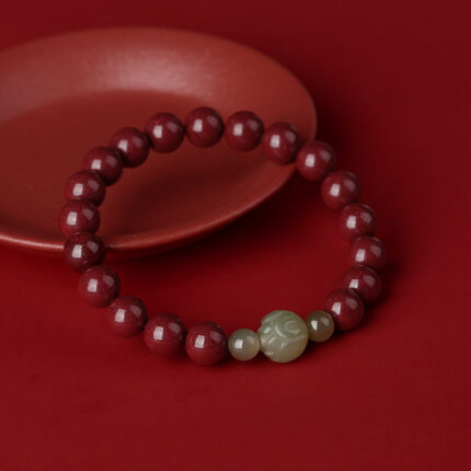 Flat-lay on dark background — the deep red of the cinnabar reads best against dark or neutral surfaces. Show the full strand with the lotus focal bead clearly visible.