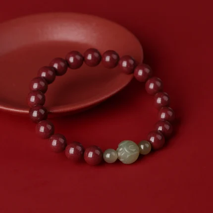 Flat-lay on dark background — the deep red of the cinnabar reads best against dark or neutral surfaces. Show the full strand with the lotus focal bead clearly visible.
