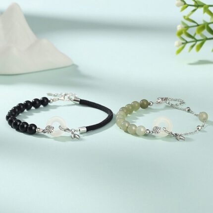 Both bracelets laid flat side by side on a neutral background — black agate version on the left, jade version on the right — showing the matching peace circle and bamboo leaf detail clearly.