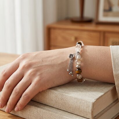 Black Gold Super Seven bracelet on wrist next to a cup of tea, soft natural morning light, calm workspace atmosphere