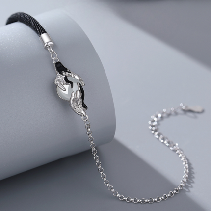 Close-up of the white agate drop charm framed by two sculpted cranes in a cloud motif on a silver setting.