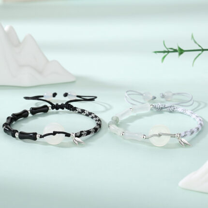 Both bracelets worn on wrists side by side — black obsidian on left, white agate on right — showing how the bamboo joint beads and peace circles relate when worn together.