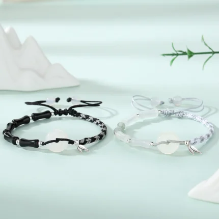 Both bracelets worn on wrists side by side — black obsidian on left, white agate on right — showing how the bamboo joint beads and peace circles relate when worn together.