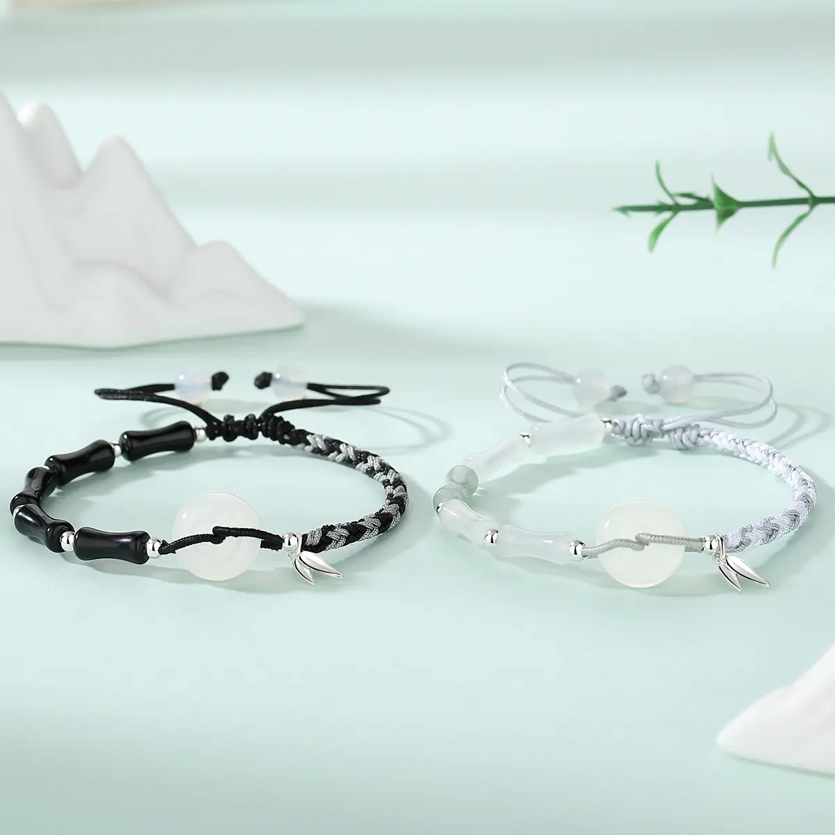 Both bracelets worn on wrists side by side — black obsidian on left, white agate on right — showing how the bamboo joint beads and peace circles relate when worn together.
