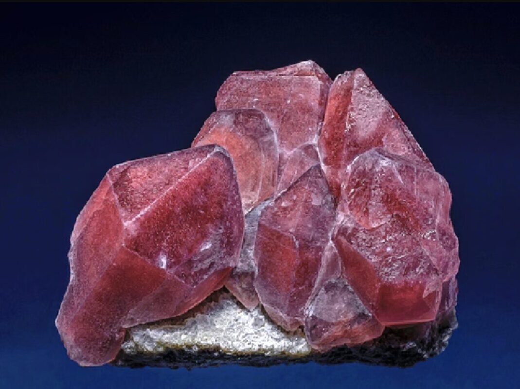 Polished strawberry quartz specimen, translucent quartz body with red-brown iron oxide inclusions scattered like seeds, characteristic natural pattern, warm light background