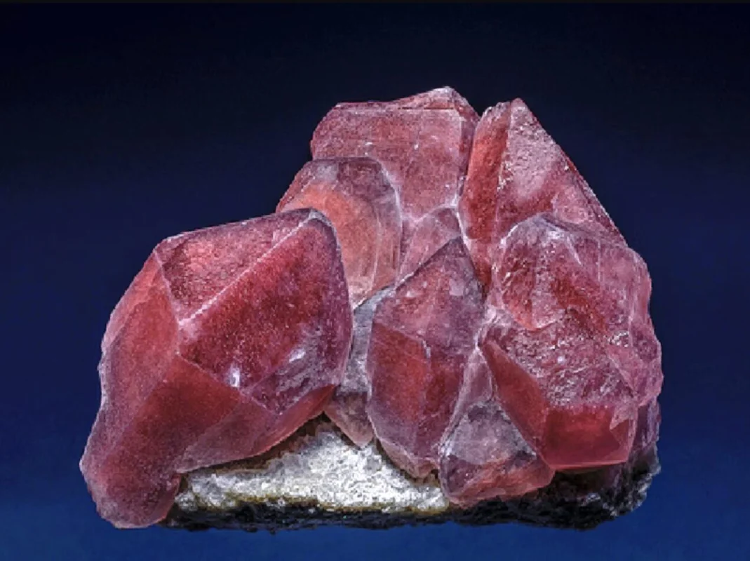 Polished strawberry quartz specimen, translucent quartz body with red-brown iron oxide inclusions scattered like seeds, characteristic natural pattern, warm light background